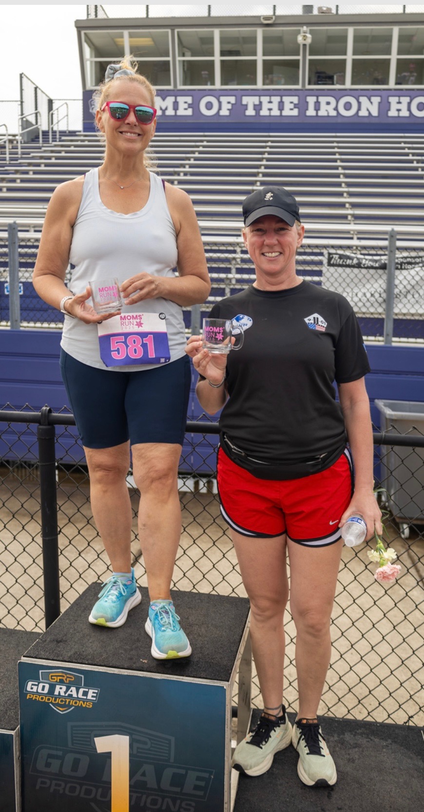 Cyndee Cave standing on a podium after winning her age group at the Mom's Day 5K race.